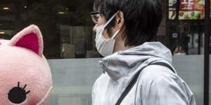 A costumed character reminds passersby in Tokyo of the dangers of COVID.