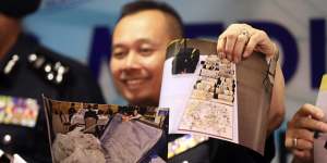 An officer of Malaysia's Federal Commercial Crime Investigation Department shows pictures of jewellery seized from Najib.