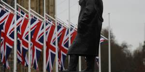 Union Jack flags hang outside Parliament near a statue of former prime minister Winston Churchill. 