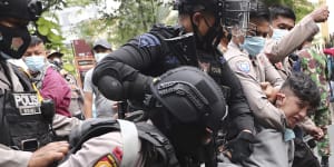 Police officers scuffle with an Afghan refugee during a rally outside the building that houses the UNHCR representative office in Jakarta,Indonesia,on Tuesday,August 24,2021. 