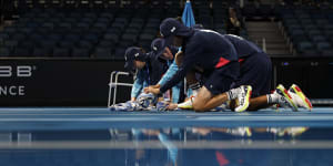 Ball kids dry off the courts after rain stopped play at the Australian Open. 
