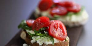 Ricotta cheese on toast with sliced tomatoes and rocket