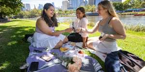 Nalini Harve (left),Shaina Mittal (middle),and Valerie Klingenbeck (right) having a picnic by the Yarra River.