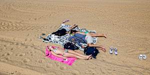 Flat out:Beachgoers relaxing on the sand on St Kilda beach on Thursday.