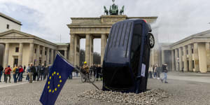 An installation by Greenpeace activists shows an SUV that is seemingly rammed into the pavement in front of the Brandenburg Gate in Berlin,
