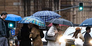 People crossing a Sydney CBD street in the rain on Thursday.