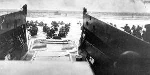 American infantrymen wade ashore off the ramp of a Coast Guard landing craft during the invasion of the French coast of Normandy in World War II. 