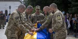 Soldiers fold a Ukrainian flag on the coffin of a colleague killed by the Russian troops in Kyiv,Ukraine.