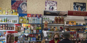 Olga Kotesova serves a customer,some of whom live in a buffer zone between separatists and Ukrainian government forces,at her small shop in Hranitne,Ukraine.