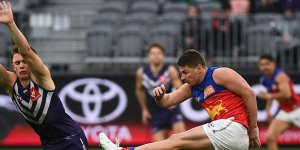 Dayne Zorko kicks the ball as Caleb Serong moves in. 