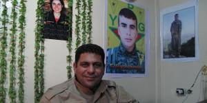 Hamid Derik,who is training new conscripts to Rojava's army,sits under a picture of 22-year-old Arin Mirkan,who ran into a group of Islamic State soldiers and blew herself up.