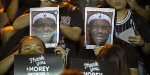 Demonstrators hold up photos of LeBron James grimacing during a rally in Hong Kong.