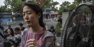 A woman cools herself in front of a misting fan in Beijing,China,on June 23.