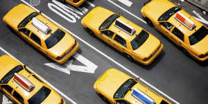 A fleet of yellow taxi cabs make their way down the street of Broadway in New York City.