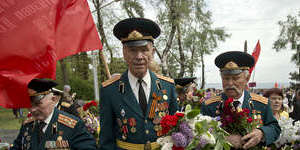 World War II veterans carry flowers given to them by people attending Victory Day celebrations on Friday.