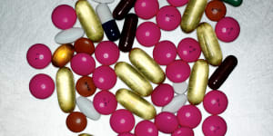 Assorted coloured pills by pill bottle,close up