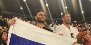 Russian fan Eugene Routman (left) and his friend Duran Raman hold up the Russian flag after Daniil Medvedev’s win on Rod Laver Arena. 