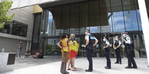 Police speak with protesters outside the ACT Magistrates Court during a hearing for the man who has been charged with alleged arson at Old Parliament House.