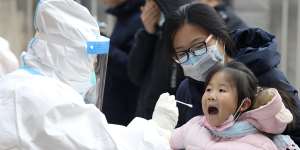 A worker in a protective suit takes a swab from a child for a coronavirus test in Shijiazhuang in China’s Hebei Province last year. 