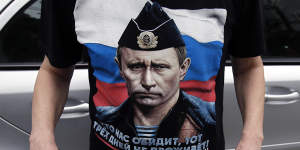 A man wearing a shirt showing a picture of Russian President Vladimir Putin holds an anti NATO poster during a protest outside the Syrian embassy in Belgrade,Serbia,on Sunday.