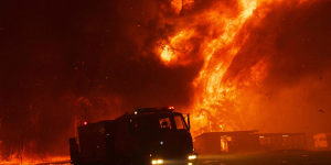 A fire truck escapes the scene after being overwhelmed by flames at the bushfire in Orangeville.