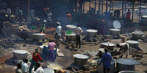 Refugees prepare food including maize porridge donated by USAID during a visit of UN officials to Uganda.