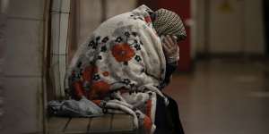 An elderly woman sits on a bench wrapped in a blanket in a subway station turned into a shelter in Kyiv,Ukraine.