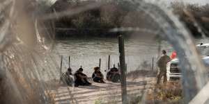Migrants wait to be processed by border patrol along the banks of the Rio Grande in Eagle Pass last week.