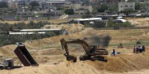 A backhoe removes sand barriers to create a buffer zone near entrances to tunnels in Rafah,along the Egyptian border.