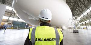 A worker stands in front of the Airlander 10 hybrid airship.