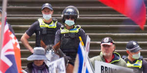 Police keep watch as protesters gather outside Parliament House on Saturday.