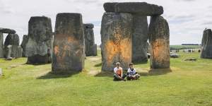 Just Stop Oil protesters sit after spraying an orange substance on Stonehenge.