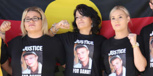 Danny Whitton’s mother and two sisters stand in front of an Aboriginal flag outside the NSW Coroners Court in February.