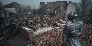 A statue of a Soviet soldier against the background of a house of culture destroyed by rocket fire on the outskirts of the city in Avdiivka,Ukraine. 