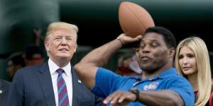 Donald Trump and his daughter Ivanka Trump watch as former football player Herschel Walker throws a football during a White House event in 2018