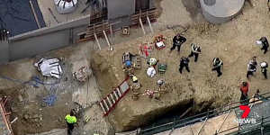 The crane dropped its load of concrete into a pit where three men were working.