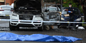 Police examine one of the burnt Audi Q7s in Berala on Wednesday.