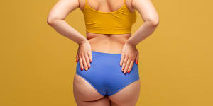 Woman in colorful underwear with toned buttocks on yellow background,body care concept underwear,woman,body image,women's health