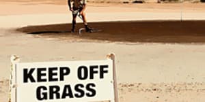 A local rakes out the green of the Coober Pedy Golf Course