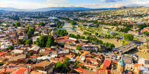 Squished between Europe and Asia,the Georgian capital of Tbilisi is a city in bloom,set in a dramatic valley through which the Mtkvari river flows. 