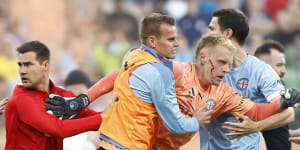 A bleeding Tom Glover of Melbourne City being escorted from the pitch on December 17,2022.