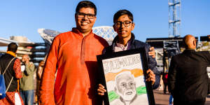 Saurabh Mishra and his son Aarav from Schofields with a drawing of Modi outside the Qudos Bank Arena on Tuesday. 