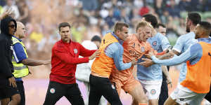 A bleeding Tom Glover of Melbourne City is escorted from the pitch by teammates.