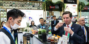 Trade Minister Simon Birmingham trying vitamin drinks at the Swisse stand on day one of the China International Import Expo in Shanghai this week.