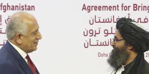 US peace envoy Zalmay Khalilzad,left,and the Taliban’s Mullah Abdul Ghani Baradar shake hands after signing a peace agreement in Doha,Qatar in February 2020.
