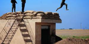 Three young YPG fighters prepare to leap from their lookout near the village of Tel Marouf,freed from the Islamic State two days before. 