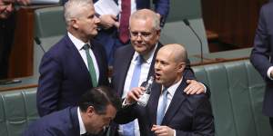 Treasurer Josh Frydenberg is congratulated by Prime Minister Scott Morrison and other colleagues after delivering the budget.