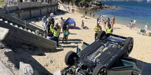 ‘Very scary’:Car smashes through north shore beach wall,flips onto sand