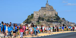 Tourists swamp France’s Mont Saint Michel.