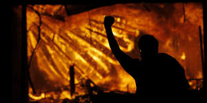 A protester gestures in front of the burning third precinct building of the Minneapolis Police Department on Thursday.